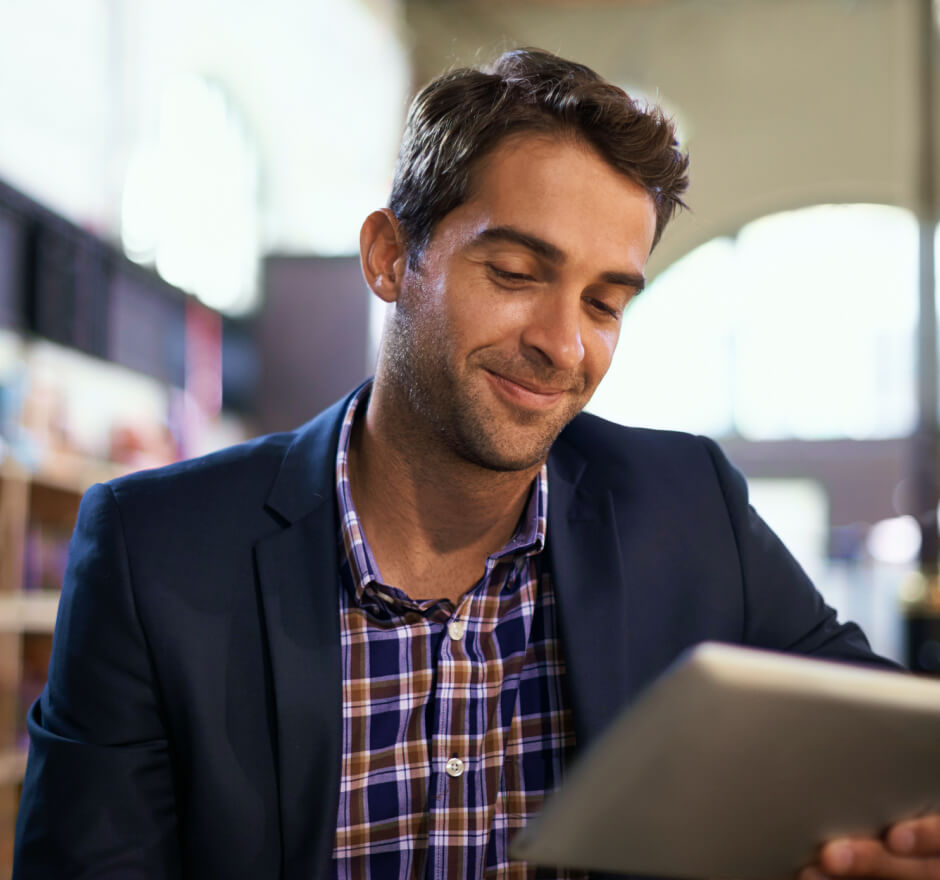 Young man wearing a casual suit smiling down at a table he is holding.