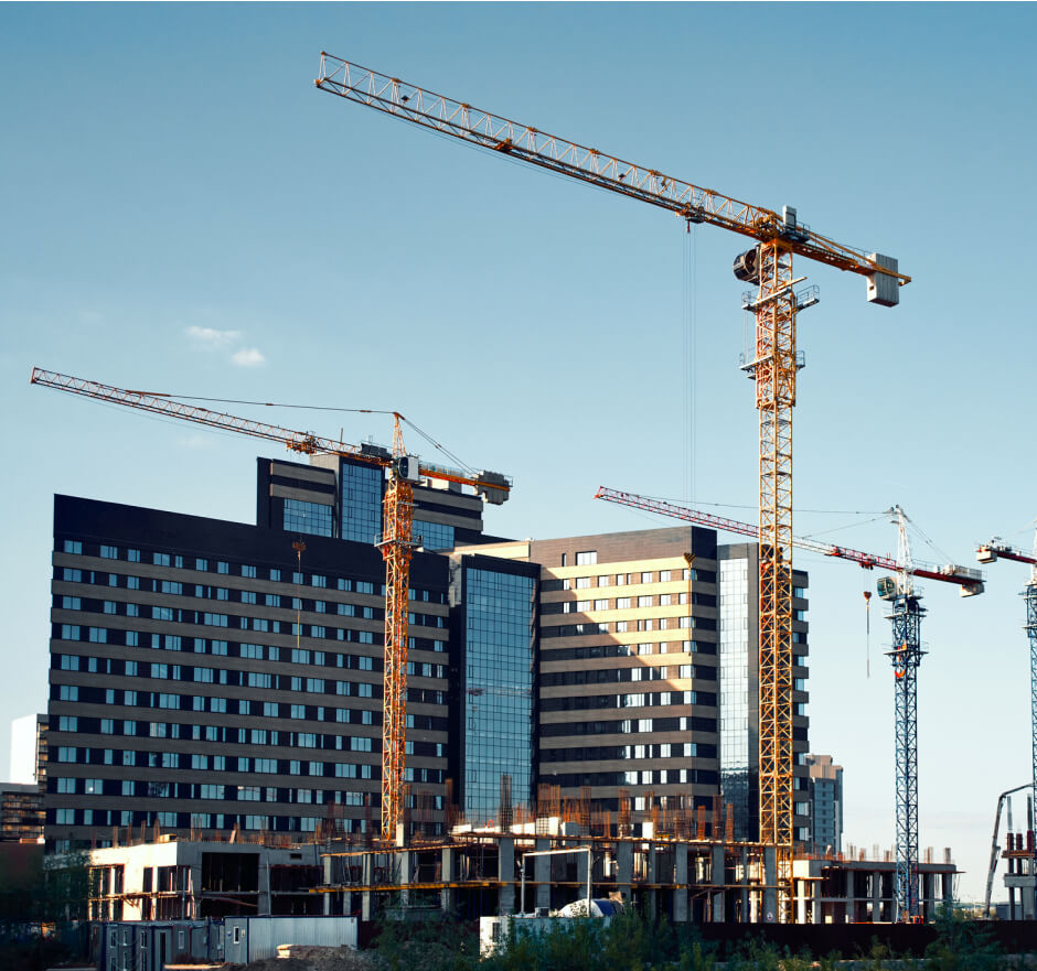 Construction site in a city with cranes that are working on tall buildings.